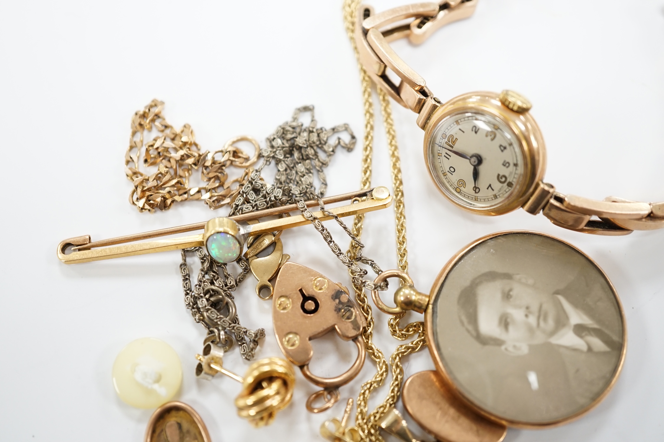 A lady's yellow metal manual wind wrist watch, on a 9ct expanding bracelet, a modern 9ct gold and white opal set pendant, on a 375 chain and other minor jewellery including a pair of 9ct gold knot earrings.